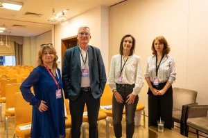 Photo de groupe : Quatre personnes posent ensemble dans une salle de conférence : Laura Frunzeti ; Stéphane Martin ; Claire Decommer
